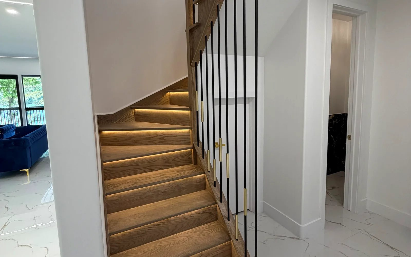 Illuminated custom wood staircase with black and brass rail details