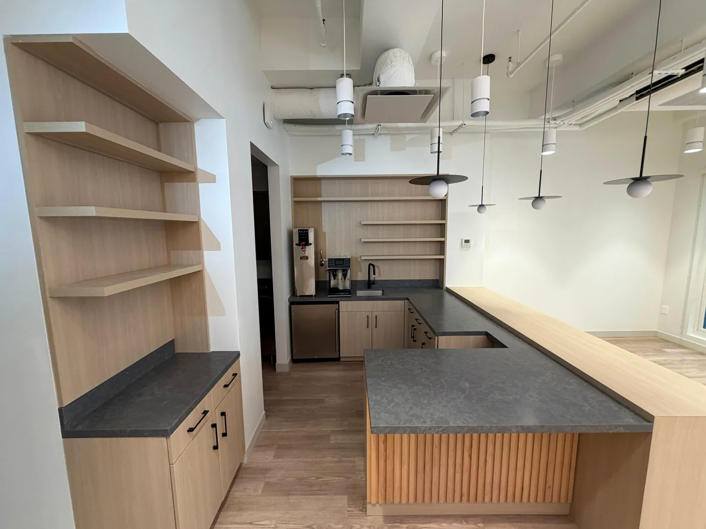 Commercial interior with custom light-wood millwork, dark counters, and coordinated lighting