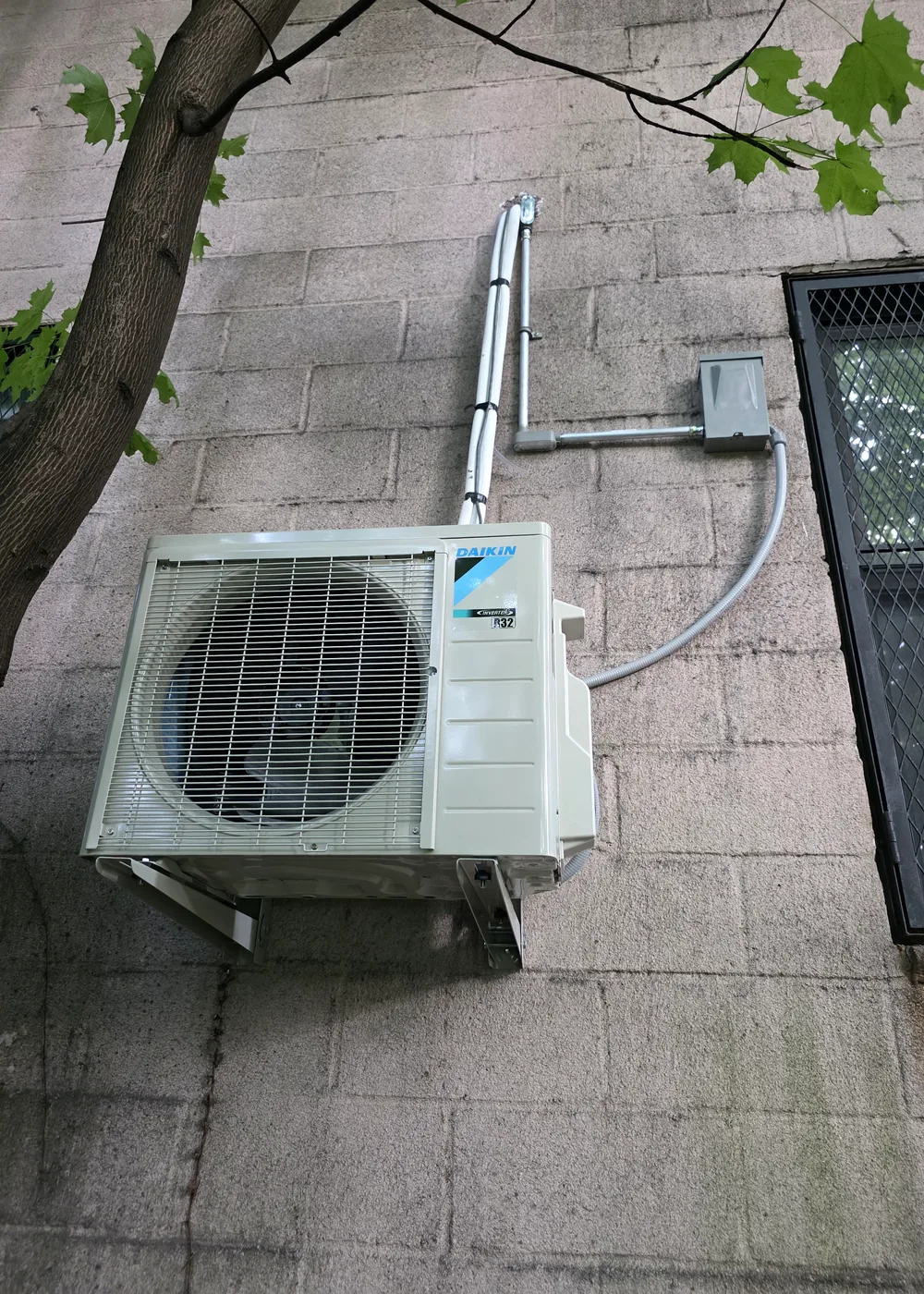 Exterior heat-pump condenser with protected refrigerant and electrical lines